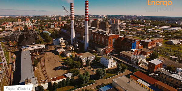 Аэроснимок ТЭЦ с красно-белыми трубами, градирнями и угольным складом в городе