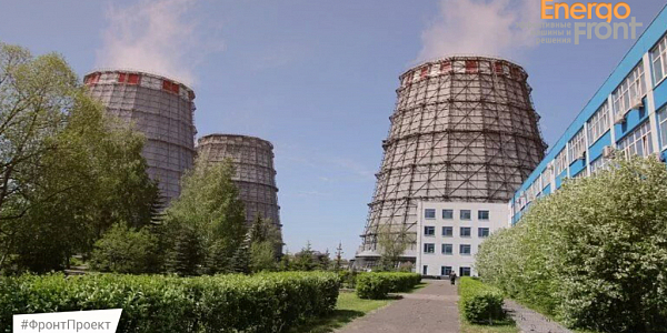 Три решетчатые градирни и синий корпус здания на озелененной площадке