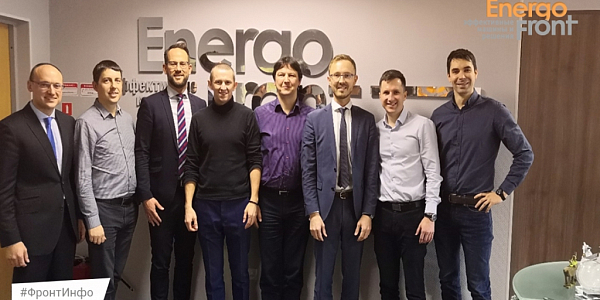 Восемь мужчин в деловой одежде у настенного логотипа Energo Front