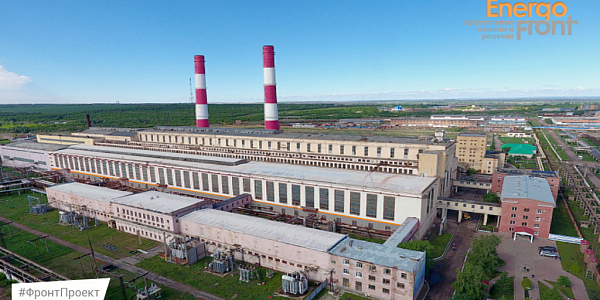 Аэроснимок длинного корпуса ТЭС с двумя полосатыми трубами среди полей