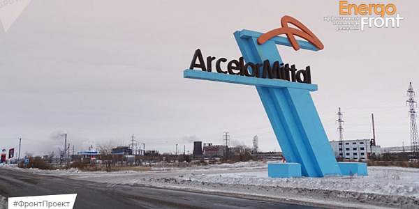 Зимний стеллаж-монумент ArcelorMittal на фоне заводских труб и снега